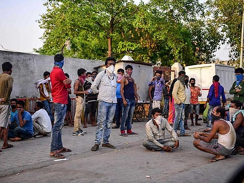 Migrant workers rest at a roadside as they travel on a truck to return to their hometowns after the government eased a nationwide lockdown as a preventive measure against the COVID-19 coronavirus, in Allahabad on May 14, 2020.
