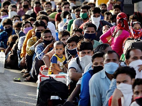 Migrant workers and their families wait for transport to reach a railway station to board trains to their home state of Uttar Pradesh, after a limited reopening of India's giant rail network following a nearly seven-week lockdown to slow the spreading of the coronavirus disease (COVID-19), in Ahmedabad, India, May 14, 2020.