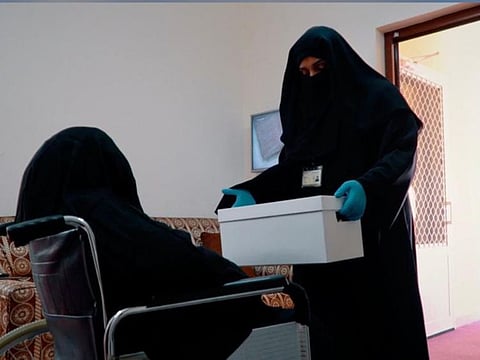 'Secure Together' campaign volunteers make a delivery to an elderly woman in Dubai