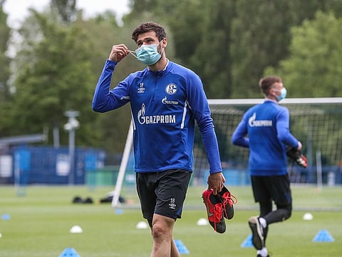 Schalke's German midfielder Daniel Caligiuri wears a face mask as he leaves after a training session.