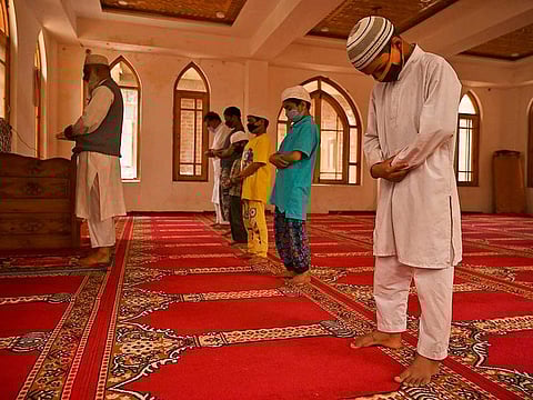 Muslim orphans wearing facemasks pray while maintaining social distancing inside an orphanage centre during Ramadan in Srinagar on May 11, 2020. The United States on May 14, 2020 voiced alarm over the targeting of religious minorities in both India and Pakistan, warning against a search for internal scapegoats during the coronavirus pandemic.