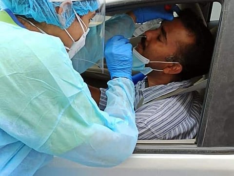 Friends pictured nurse Sandhya Shyju conducting a drive-through COVID-19 test on her husband Shyju