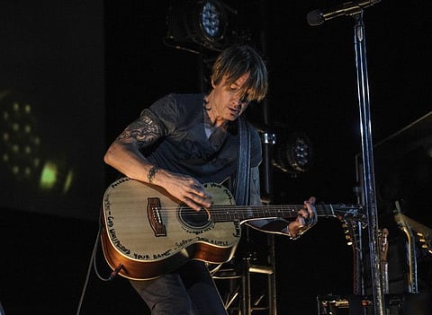 This image released by Guitar Monkey Entertainment shows Keith Urban, center, performing for first responders at the Stardust Drive In Theatre in Watertown, Tenn. on Thursday, May 14, 2020. The private show was set up exclusively for more than 200 doctors, nurses, emergency medical technicians and staff from Vanderbilt Health, part of Vanderbilt University Medical Center. (Andy Snyder/Guitar Monkey Entertainment via AP)
