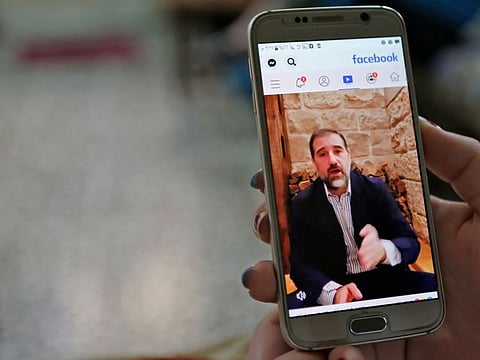 A woman watches the Facebook video of Syrian businessman Rami Makhlouf on her mobile in Syria's capital Damascus, on May 11, 2020. Syria's top tycoon publicly airing his grievances has revealed a power struggle within the ruling family as it tries to cement its power after nine years of war, analysts say.
