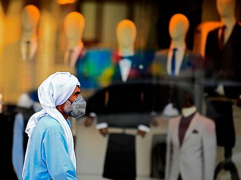 A man wearing a protective mask walks past a clothing shop in Dubai. Picture for illustrative purposes only.