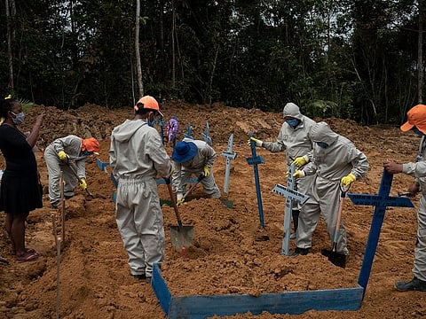 Cemetery workers place crosses over a common grave after burying five people at the Nossa Senhora Aparecida cemetery amid the new coronavirus pandemic in Manaus, Brazil, Wednesday, May 13, 2020.