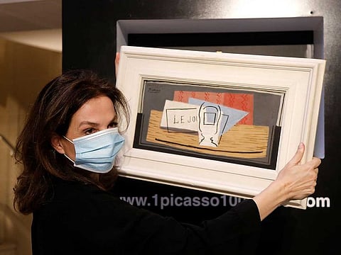 Raffle organizer Peri Cochin, wearing a protective face mask, poses with the painting "Nature Morte, 1921" by Spanish painter Pablo Picasso after the charity raffle official draw to designate the winner of the Picasso oil painting for 100 euros at Christie's auction house in Paris.