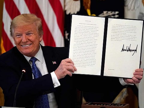 US President Donald Trump holds up an executive order limiting regulations to support economic recovery during a Cabinet Meeting in the East Room of the White House, Tuesday, May 19, 2020, in Washington.