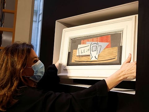 Raffle organizer Peri Cochin, wearing a protective face mask, poses with the painting "Nature Morte, 1921" by Spanish painter Pablo Picasso after the charity raffle official draw to designate the winner of the Picasso oil painting for 100 euros at Christie's auction house in Paris