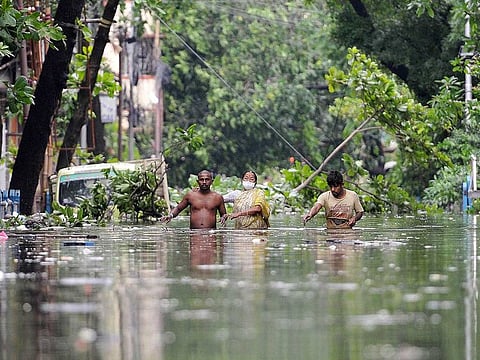 Residents make their way through uprooted trees and waterlogged streets, caused due to the heavy rainfall accompanied by the Super Cyclone Amphan, in Kolkata on Thursday.