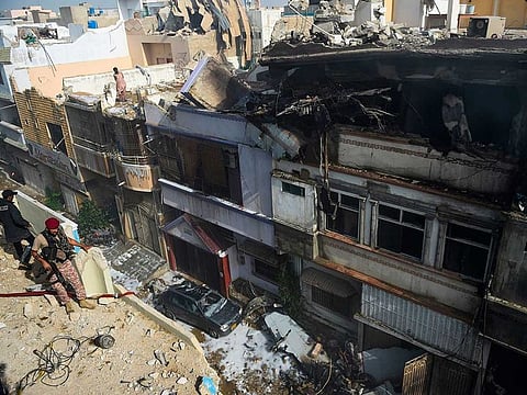 Security personnel stand on a roof next to damaged houses after a Pakistan International Airlines aircraft crashed in a residential area in Karachi.