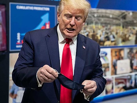 President Donald Trump holds his protective face mask as he speaks while touring Ford's Rawsonville Components Plant that has been converted to making personal protection and medical equipment.