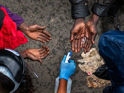 Homeless people waiting to receive food baskets from private donors, get their hands sanitised April 13, 2020, in Johannesburg. Because of South Africa's imposed lockdown to contain the spread of COVID-19, many are not able to work.