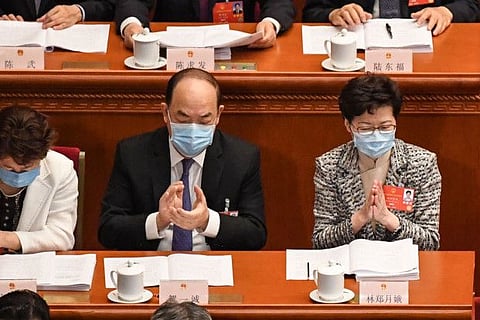 Hong Kong Chief Executive Carrie Lam (R) and Macau Chief Executive Ho Iat Seng (C) attend the opening session of the National People's Congress (NPC) at the Great Hall of the People in Beijing on May 22, 2020.