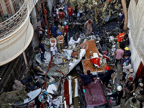 Rescue workers gather at the site of a passenger plane crash in a residential area near an airport in Karachi, Pakistan, May 22, 2020.
