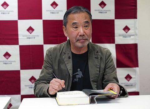 Japanese novelist Haruki Murakami signs his autograph on his novel "Killing Commendatore" during a press conference at Waseda University in Tokyo Saturday, Nov. 3, 2018. (AP Photo/Eugene Hoshiko)