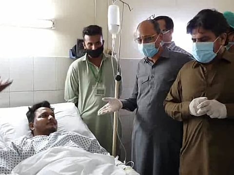 In this photo released by the Sindh Press Information Department, Pakistani provincial minister Saeed Ghani, second from right, meets Mohammad Zubair who survived a plane crash, at a hospital in Karachi on Friday, May 22.