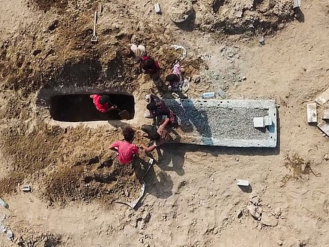 In this May 21, 2020, photo, grave diggers bury a body at Radwan Cemetery in Aden, Yemen. At a cemetery in Yemen’s largest southern city, dozens of fresh graves are a testament to a spike in deaths amid the coronavirus pandemic.