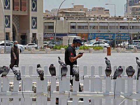 A man wearing a protective mask checks his phone as he walks by at Qatar's touristic Souq Waqif bazar in the capital Doha.