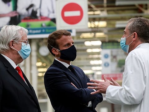 French President Emmanuel Macron, wearing a protective mask, speaks with Valeo CEO Jacques Aschenbroich and General Manager Alberto Santos as he visits a factory of manufacturer Valeo in Etaples, near Le Touquet, France May 26, 2020, as part of the launch of a plan to rescue the French car industry.
