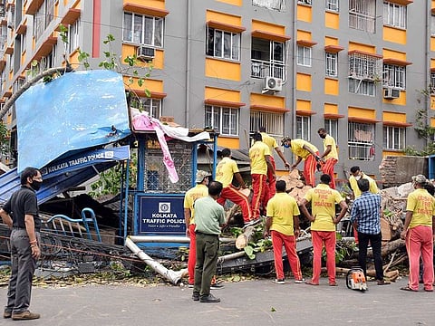 Disaster management personnel removing uprooted trees from the roads after cyclone Amphan, in Kolkata on Monday.