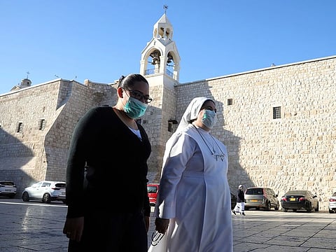 Christians walk towards the Church of the Nativity that reopened Tuesday to visitors after a nearly three-month closure due to the coronavirus pandemic, in Bethlehem, West Bank, Tuesday, May 26, 2020.