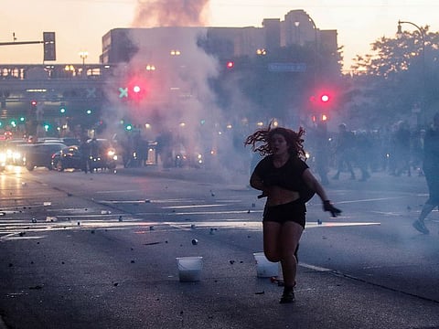 A woman reacts on a street as tear gas is used by riot police to disperse protesters as demonstrations continue after a white police officer was caught on a bystander's video pressing his knee into the neck of African-American man George Floyd, who later died at a hospital, in Minneapolis, Minnesota, U.S., May 28, 2020.