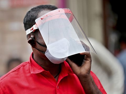 An Indian trader wears a face shield and mask as he talks on his mobile phone at a wholesale fruit market in Bengaluru on Saturday, May 30.