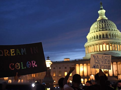 Protesters hold signs outside the Capitol in Washington, DC, on May 29, 2020 during a demonstration over the death of George Floyd, a black man who died after a white policeman kneeled on his neck for several minutes.