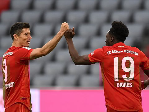 Bayern Munich's Robert Lewandowski, left, and teammate Alphonso Davies celebrate the fifth goal against Fortuna Duesseldorf