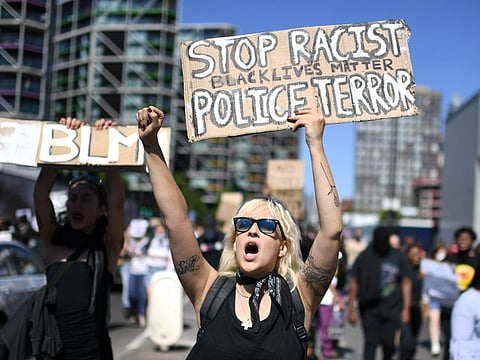 Demonstrators carry placards with slogans as they march in the road outside the US Embassy in London on May 31, 2020 to protest the death of George Floyd, an unarmed black man who died after a police officer knelt on his neck for nearly nine minutes during an arrest in Minneapolis, USA.