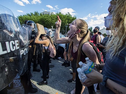 Demonstrators vent to police in riot gear as they protest the death of George Floyd, Saturday, May 30, 2020, near the White House in Washington. Floyd died after being restrained by Minneapolis police officers.