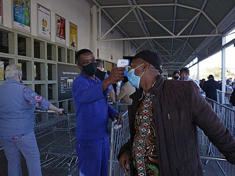 A worker measures the temperature of a customer outside Makro Silverlakes Liquor Store in Pretoria on June 1, 2020. South Africa moved into level three of a five-tier lockdown on June 1, 2020, to continue efforts to curb the spread of the COVID-19 coronavirus. Under level three, all but high-risk sectors of the economy will be allowed to reopen.