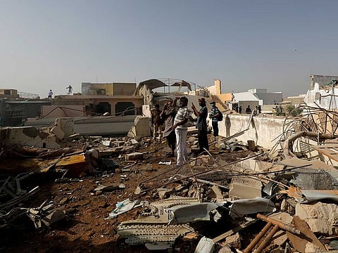 People stand on a roof of a house amidst debris of a passenger plane, crashed in a residential area near an airport in Karachi, Pakistan May 22, 2020.