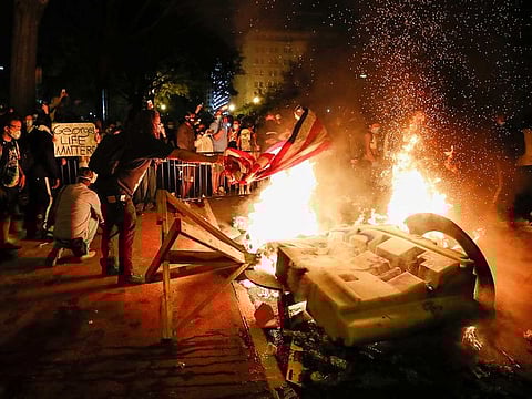 Demonstrators start a fire as they protest the death of George Floyd, Sunday, May 31, 2020, near the White House in Washington. Floyd died after being restrained by Minneapolis police officers.