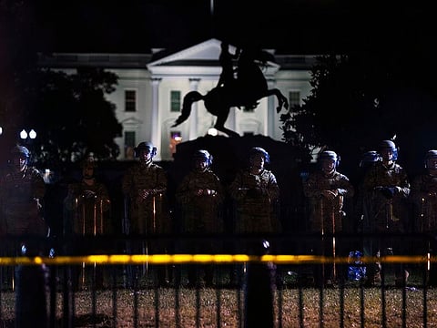 With the White House in the background, a line of police forms behind a fence in Lafayette Park as demonstrators gather to protest the death of George Floyd, Tuesday, June 2, 2020, in Washington.