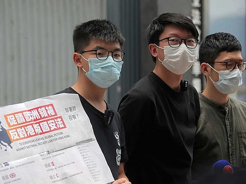 Pro-democracy activists, Joshua Wong, left, Sunny Cheung, centre, and Nathan Law holding a placard, speak to media to urge the European leaders to act against national security law for Hong Kong outside the Legislative Council, in Hong Kong, Wednesday, June 3, 2020. British Prime Minister Boris Johnson says his country stands ready to open the door to close to 3 million Hong Kong citizens if China enacts a national security law for the city.