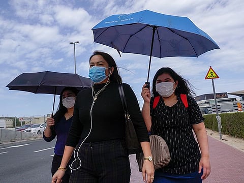 People, wearing masks as a precautionary measure, walk past a street at Business Bay area in Dubai.
