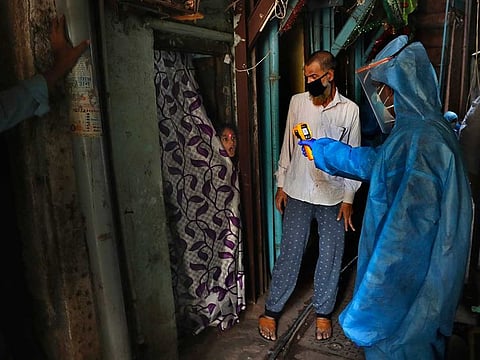 In this April 13, 2020, file photo, a doctor checks the temperature of a girl in Dharavi, one of Asia's largest slums, during lockdown to prevent the spread of the new coronavirus in Mumbai, India. Dharavi has had more than 1,800 confirmed COVID-19 cases, and is among Mumbai’s most affected pockets.