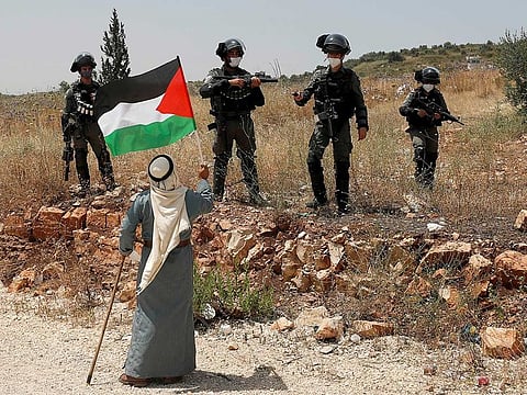A demonstrator holds a Palestinian flag in front of Israeli forces during a protest against Israel's plan to annex parts of the occupied West Bank, near Tulkarm, on June 5, 2020.