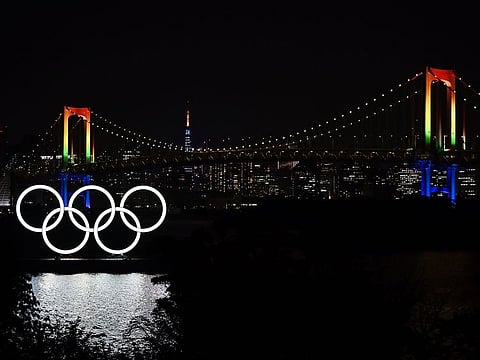 The Olympic rings, the Rainbow bridge and the Tokyo Tower are pictured at night from Tokyo's Odaiba area.