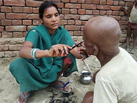 Female barber gives a villager in Bihar a shave and trim.
