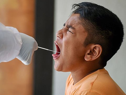 A child reacts as a medic collects his swab sample for a COVID-19 test at a hotel, converted into an isolation center for passengers arriving from Delhi by train, in Chennai.