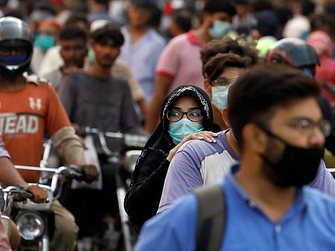 A woman rides on a motor bike as she wears a protective face mask amid the rush of people outside a market as the outbreak of the coronavirus disease (COVID-19) continues, in Karachi, Pakistan.