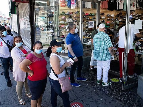 People with their face masks stand in line to enter a Sneaker Box after it reopens on June 8, 2020, in the Bronx borough of New York.