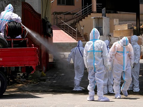 A municipal worker sprays disinfectant on his colleagues after they cremated the body of a woman who died due of COVID-19, at a crematorium in Ajmer, Tuesday, June 9, 2020.