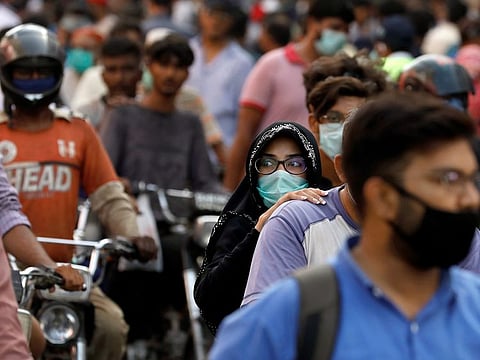 A woman rides on a motor bike as she wears a protective face mask amid the rush of people outside a market as the outbreak of the coronavirus disease (COVID-19) continues, in Karachi, Pakistan June 8, 2020.