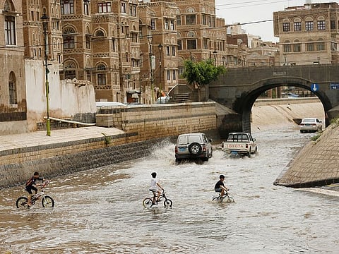 Boys ride their bicycles in flooded waters after rains in the old quarter of Sanaa