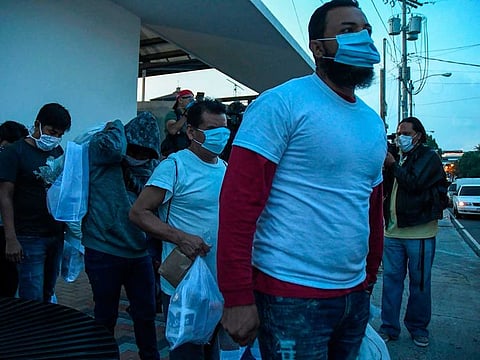 Migrants, part of a group of 50 Guatemalans deported from the United States, wear face masks as a preventive measure against the novel coronavirus COVID-19, as they get into a bus upon landing at the Air Force base in Guatemala City on June 9, 2020.