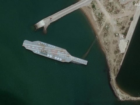 In this Monday, June 8, satellite photo provided by Maxar Technologies, a fake aircraft carrier is seen off the coast of Bandar Abbas, Iran.